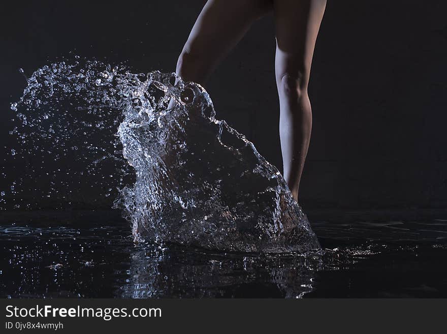 Barefoot woman dancing in water in the dark