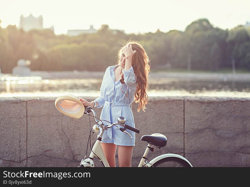 Portrait of a smiling woman with a bicycle at sunset