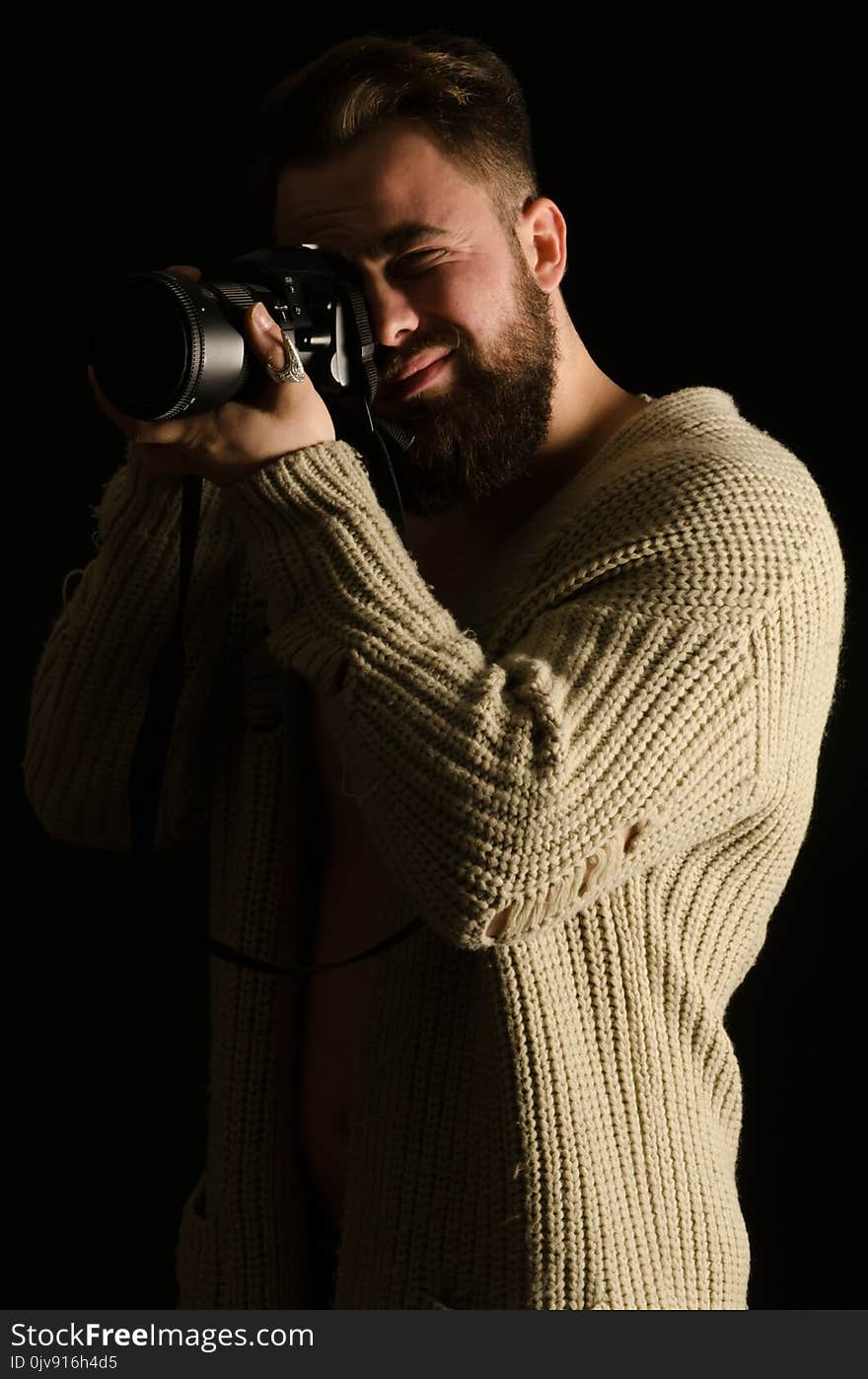 young model posing by photographing in studio, wearing cardigan, bearded