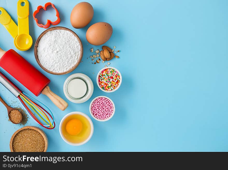 Baking background with ingredients eggs, flour, milk, sugar and cake decor on light blue table. Baking background with ingredients eggs, flour, milk, sugar and cake decor on light blue table