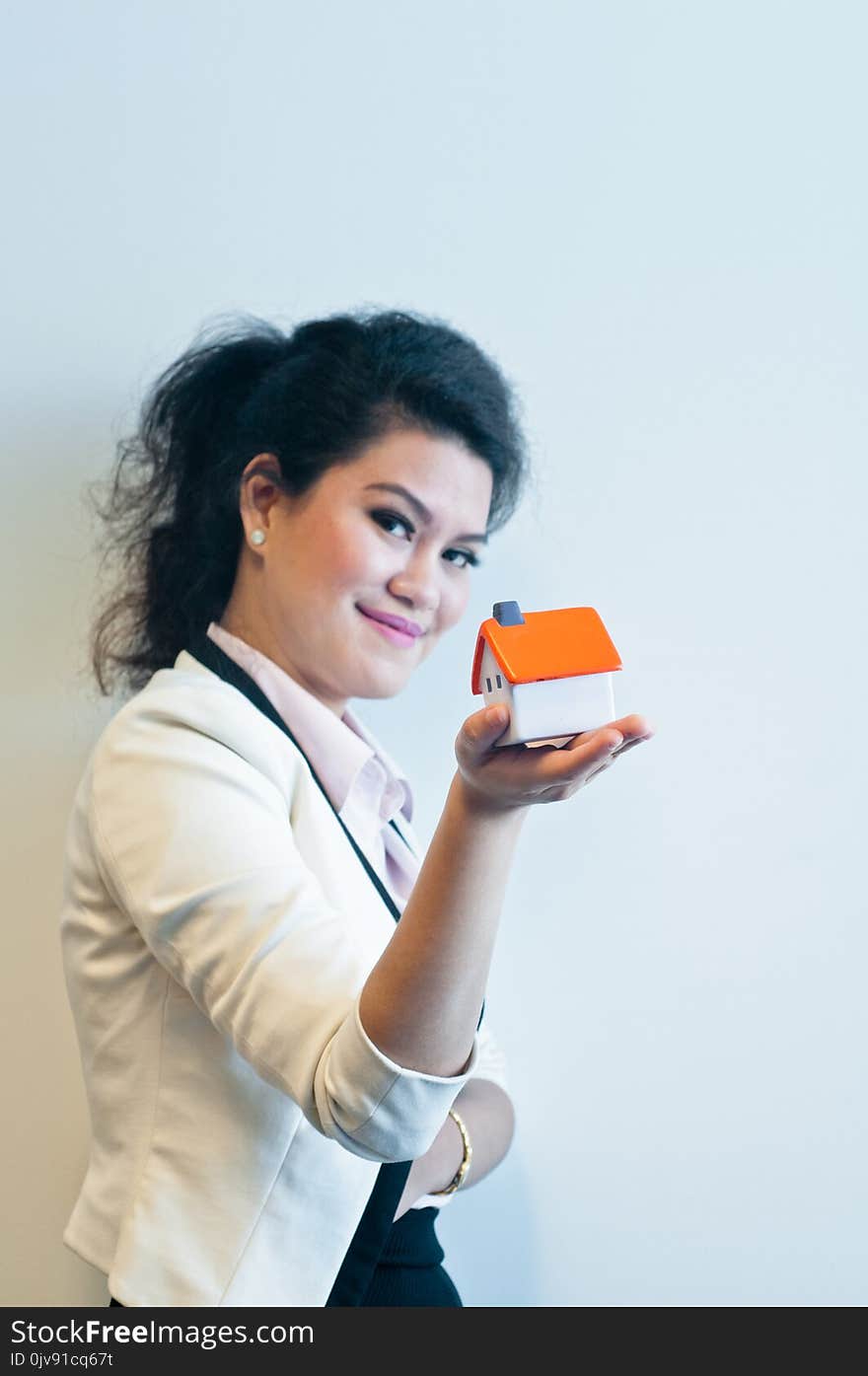 Woman looks and holds a house model on white background