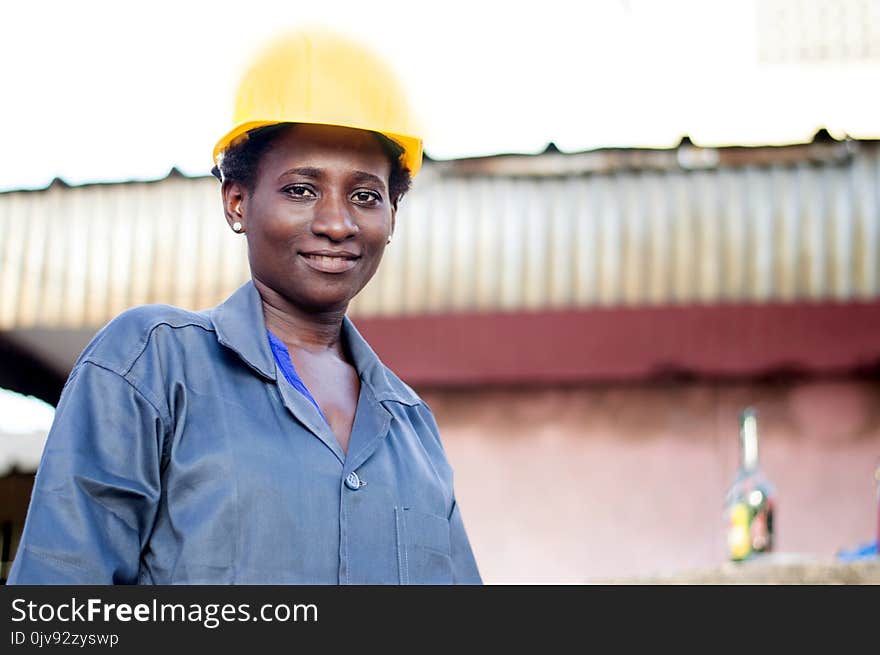 Young smiling worker standing in her workplace looks at the camera. Young smiling worker standing in her workplace looks at the camera.