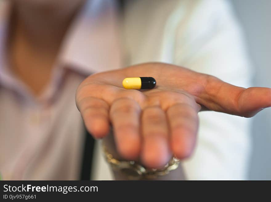 Focus of a small medicine capsule on a hand