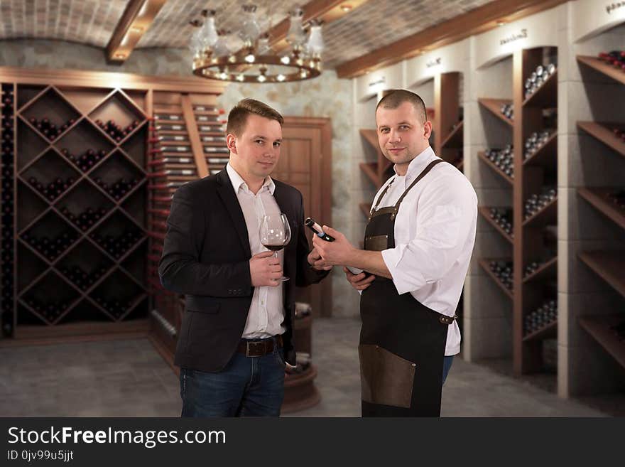 Two young professional sommeliers choosing wine in wine cellar