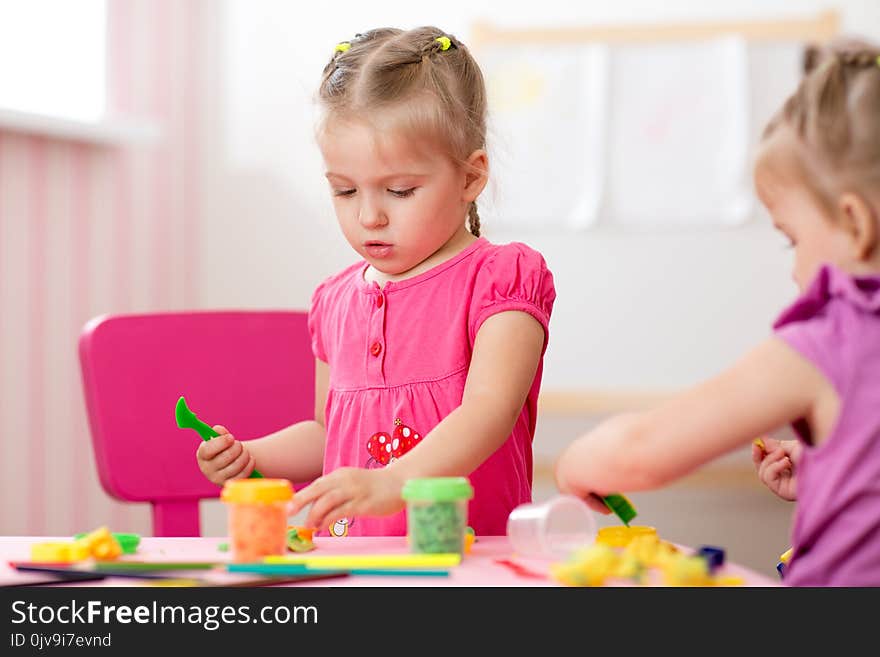 Children creativity. Kids sculpts from play clay. Cute little girl moulds from plasticine on table in nursery