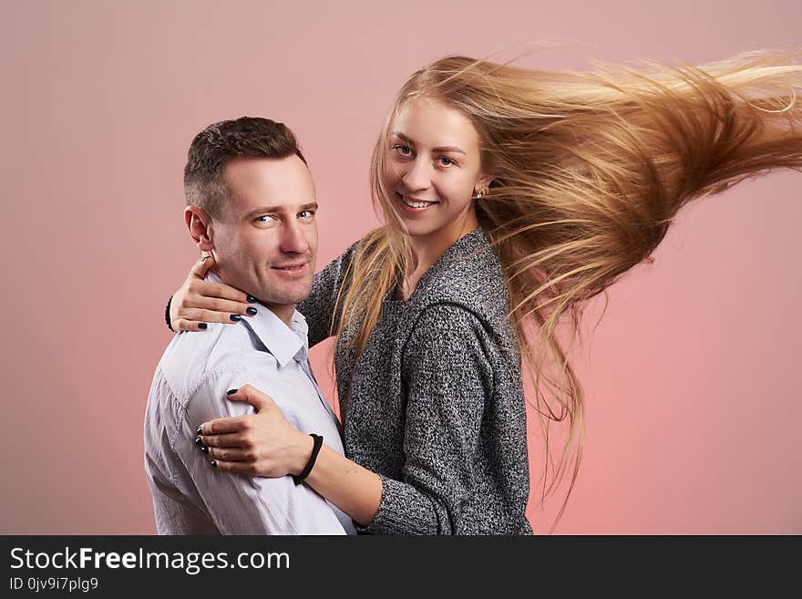 Happy smiling caucasian couple hugging isolated on pink background