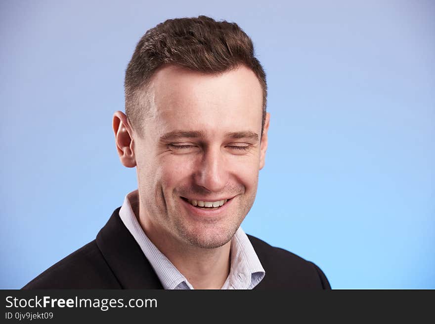 Man laugh with closed eyes on blue background close up