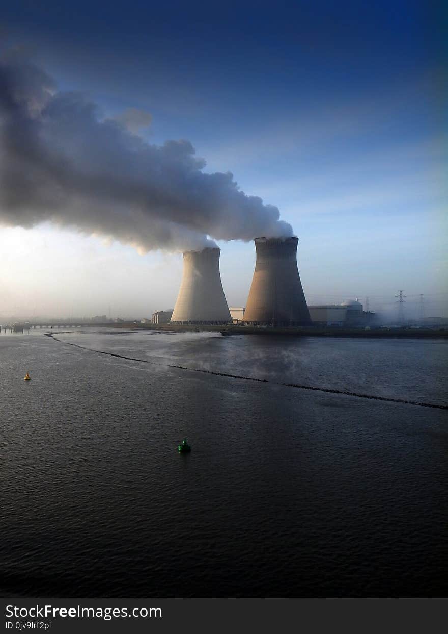 Two big funnels and smoke coming out of them. Nuclear plant in West Europe. Blue sky in the background. Two big funnels and smoke coming out of them. Nuclear plant in West Europe. Blue sky in the background.