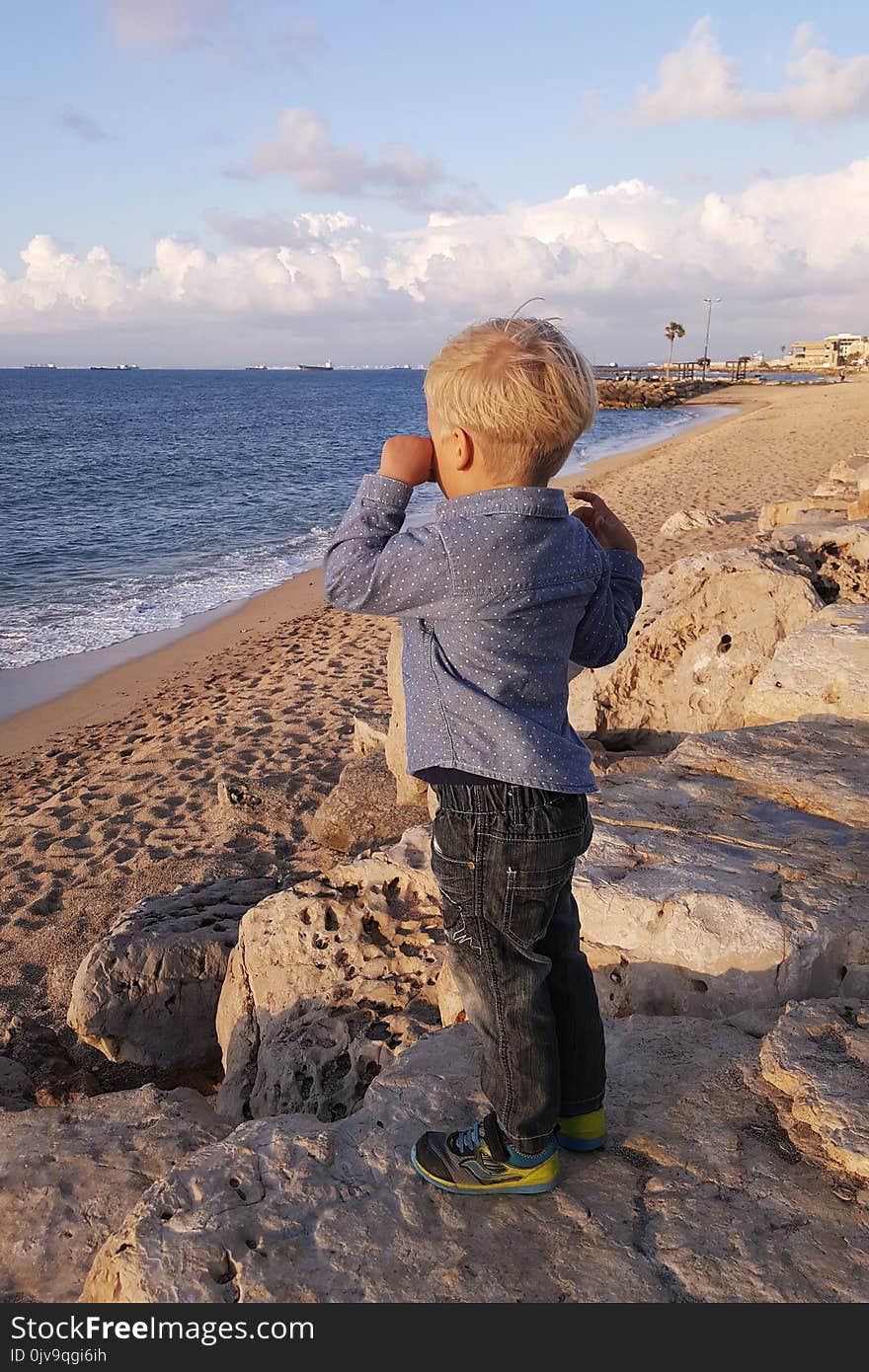 Little boy standing on beach wiping his tears, waiting and looking at ships. Haifa. Little boy standing on beach wiping his tears, waiting and looking at ships. Haifa