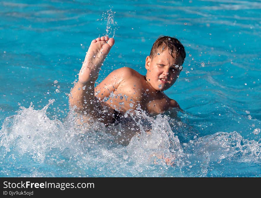 Boy swims with a splash in the water park .