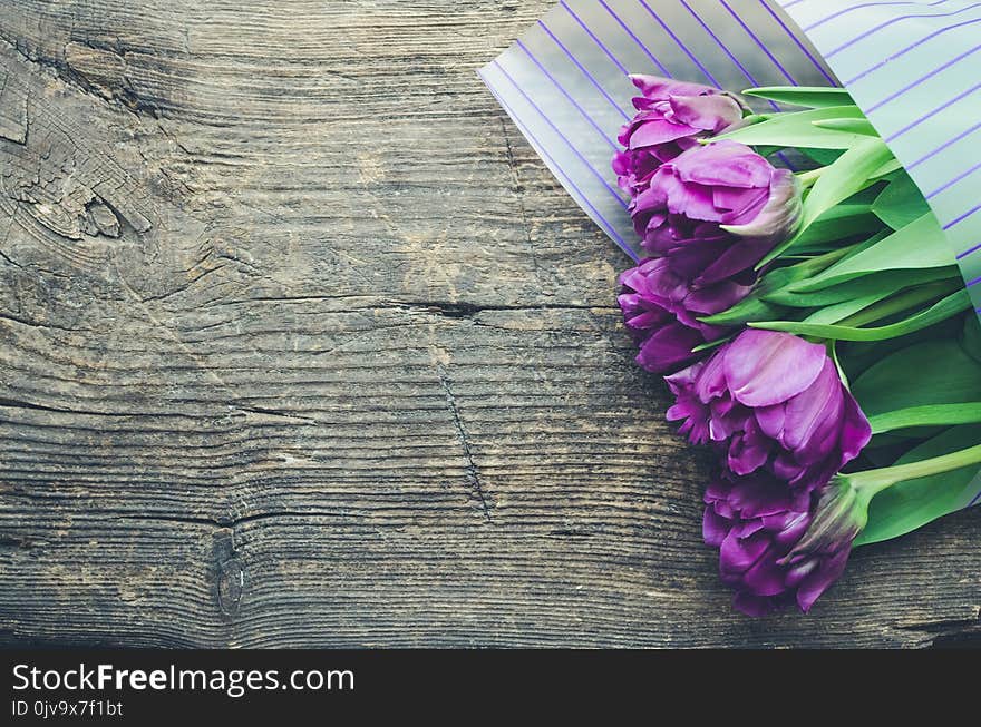 Bouquet of purple tulips on old wooden background. Valentines, Mothers, Womens Day and greeting concept. View from above with copy space. Banner template layout mockup for post blog social media.