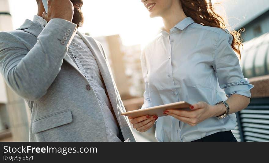 Business man and woman working outdoors with tablet computer in front of office