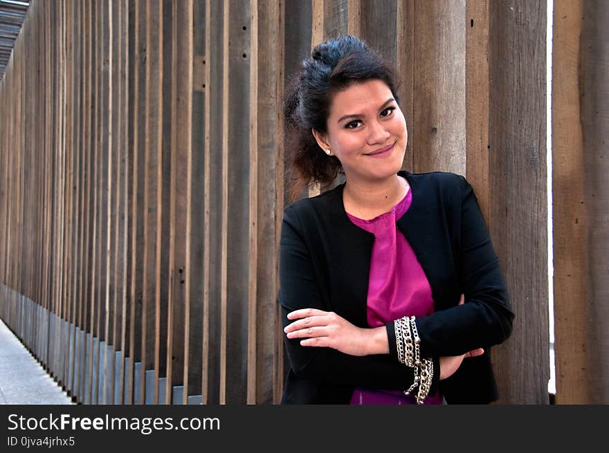 Business woman stands with big smile and with Thai silk dress and formal suit stands in front of wooden wall. Business woman stands with big smile and with Thai silk dress and formal suit stands in front of wooden wall.