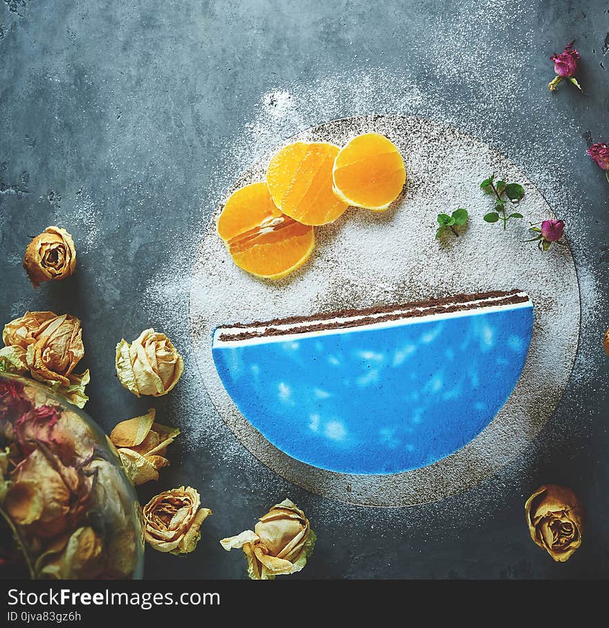 Half of cutted mousse cake with blue glaze on a dark gray concrete background