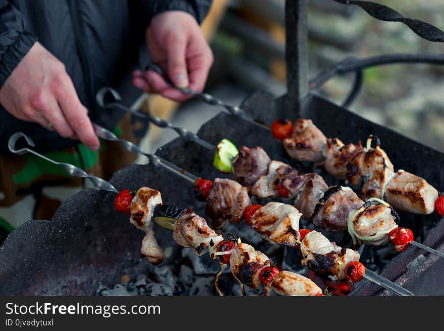 Male hand with shish kebab skewers on the grill