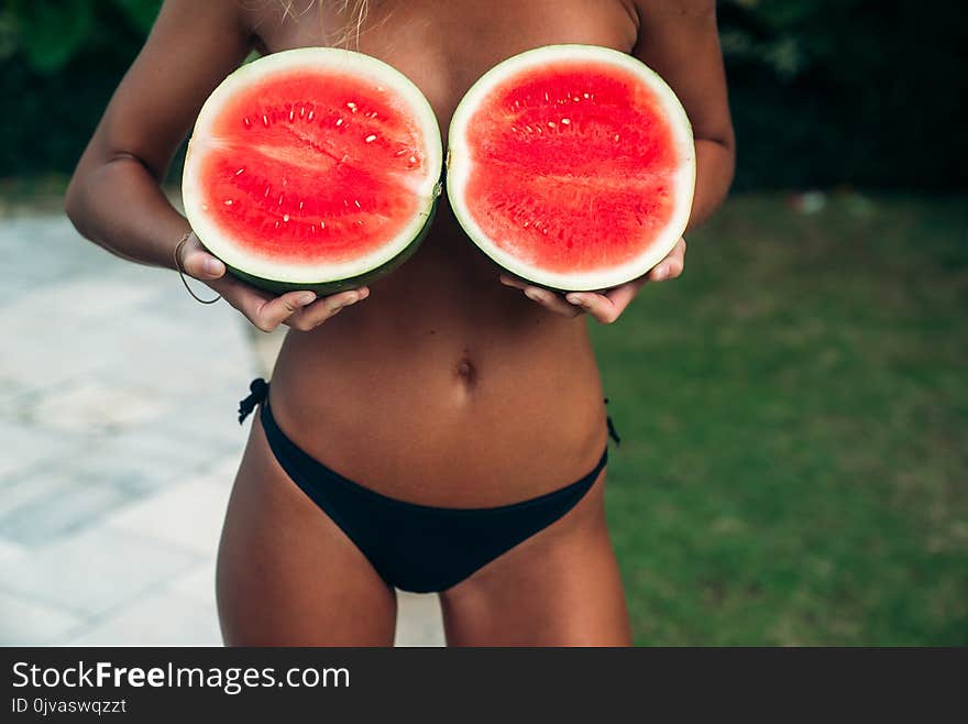 Close up girl hands holding red watermelon cover her breast. model with perfect body. Concept of sport, vegetarian