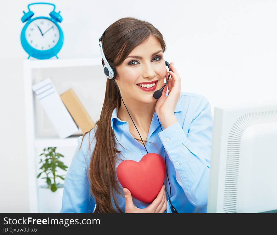 Portrait of call center smiling operator with phone headset isolated on white office background hold red heart. Help concept.