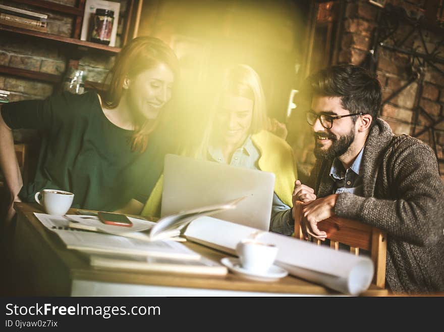 Three young student using laptop together and talking. Small group people. Three young student using laptop together and talking. Small group people.