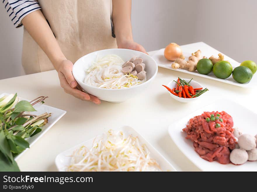 Female chef prepare traditional Vietnamese soup Pho bo with herb