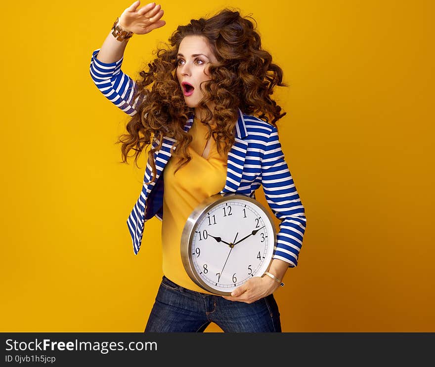 Surprised stylish woman with clock looking into distance