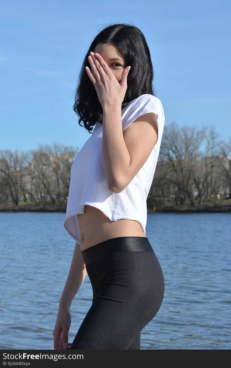 Young girl with black hair and black pants in a hiding pose. Young girl with black hair and black pants in a hiding pose