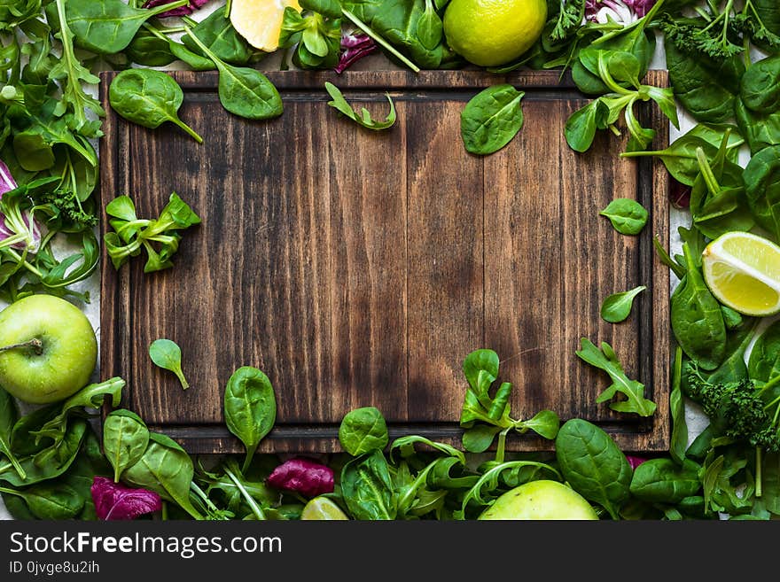 Green food background. Salad ingredients on table with cutting board and copy space. Healthy food and diet concept.