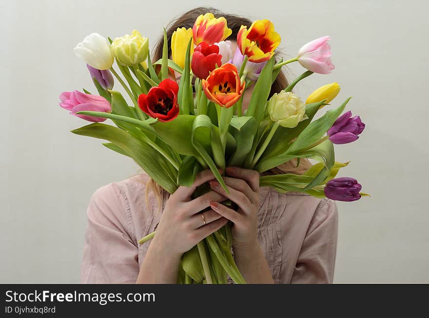 Young charming girl with a bouquet of flowers - multi-colored tulips.