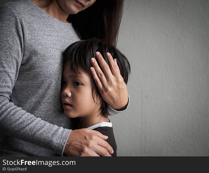 Sad little boy being hugged by his mother at home. Parenthood, Love and togetherness concept.