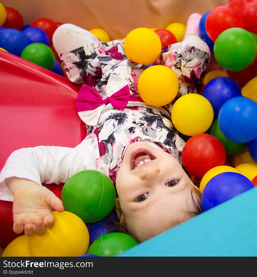 Little cute smile girl plays in balls for a dry pool. Play room. Happiness