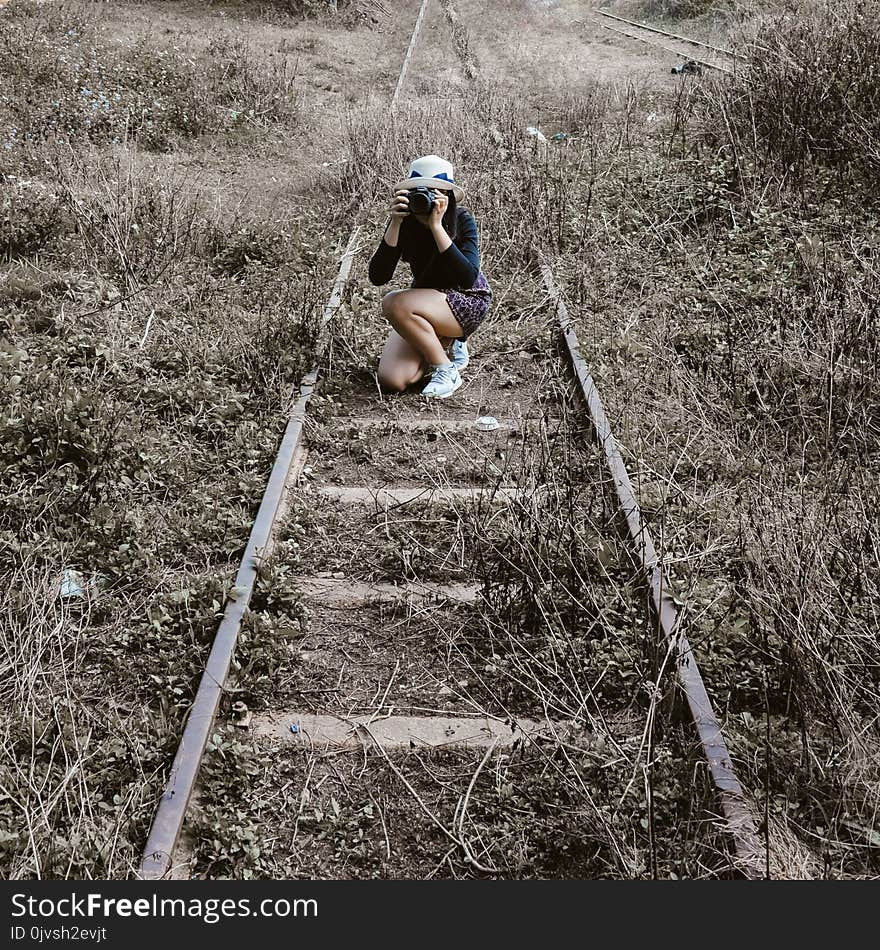 Woman White Round Hat Holding Black Dslr Camera on Rail Way