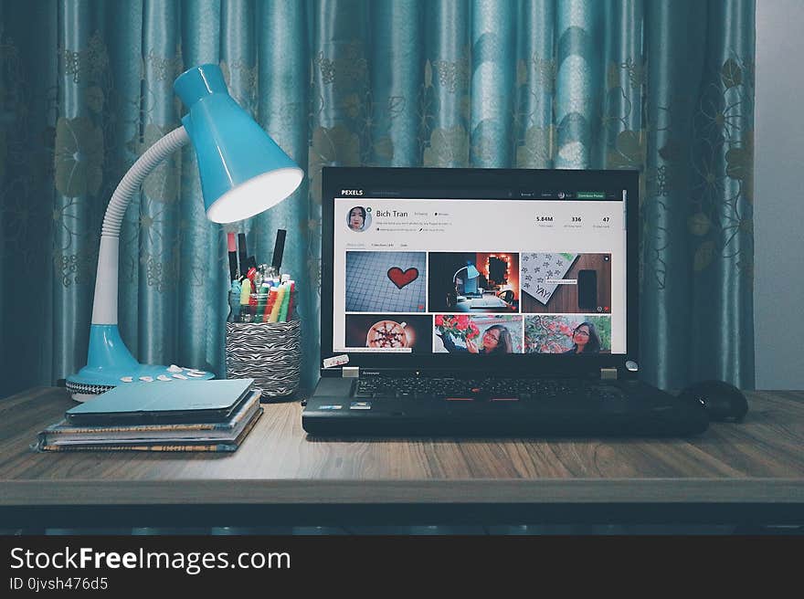 Black Laptop Computer Near Blue Study Lamp on Brown Wooden Table