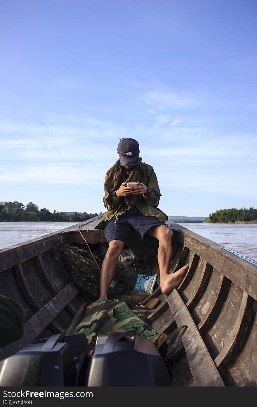 Man Wearing Black Cap Sitting Inside a Boat