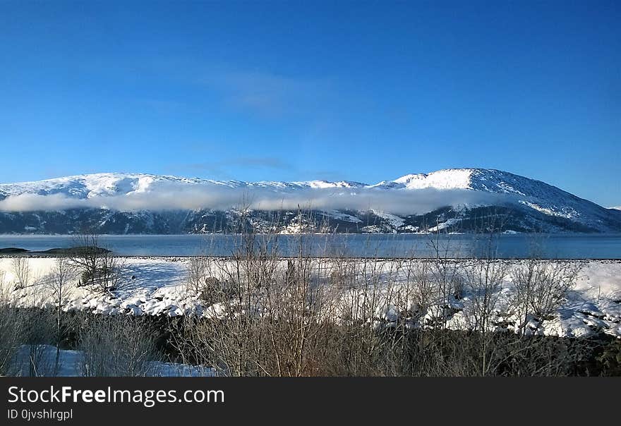 Landscape Photo of Body of Water Within Snow Coated Mountain Range