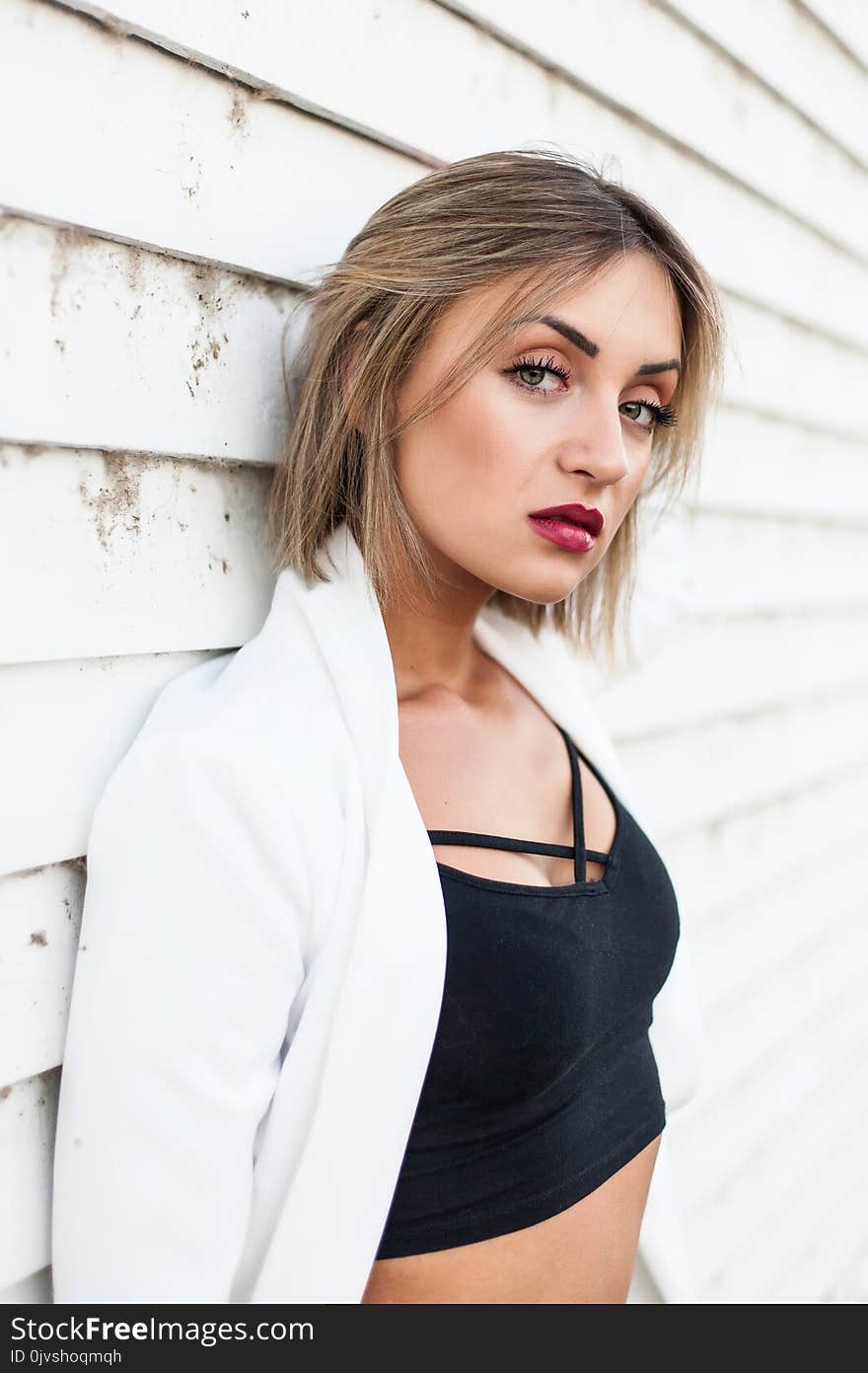 Woman Wearing Black Crop Top Leaning Against White Wall