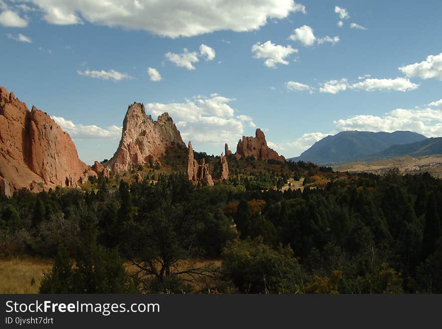 Brown Rock Formation Near Green Trees Under Cloudy Sky