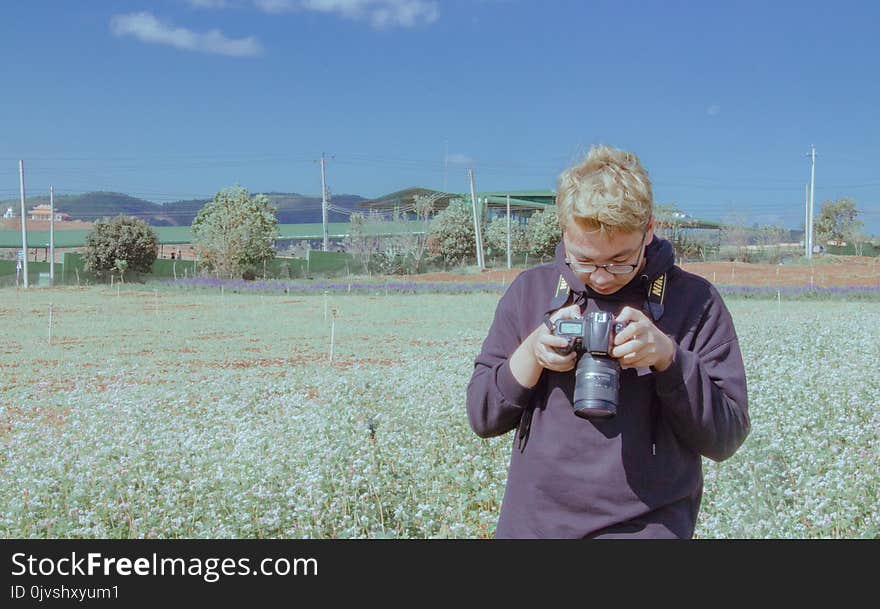 Man Holding Black Dslr Camera Under Blue Sky