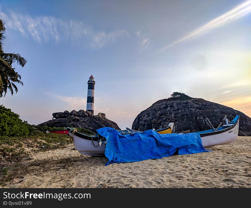 White Canoe With Blue Cover on Sand