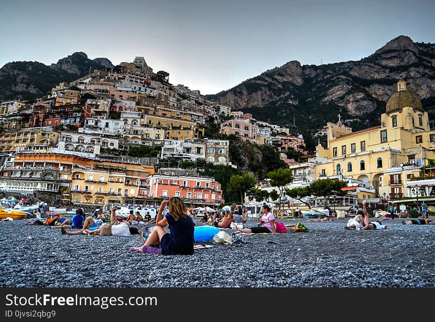 Woman Sitting on Gray Soil Near Houses