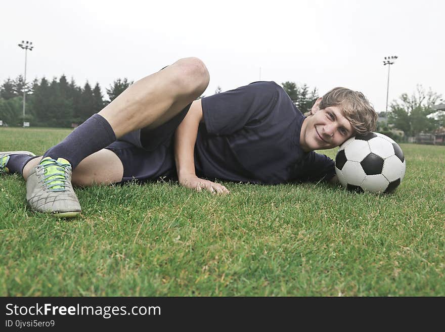 Man Wearing Black Crew-neck Shirt and Black Shorts Lying on Green Grass at Daytime