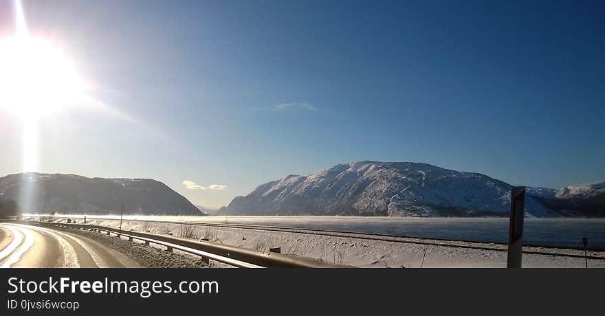 Landscape Photo of Gray Road Across Two Gray Land Formations