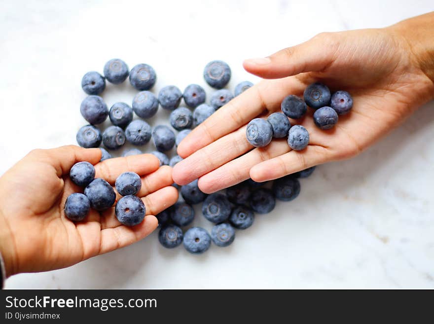 Two Person&#x27;s Hand With Blueberries on Top