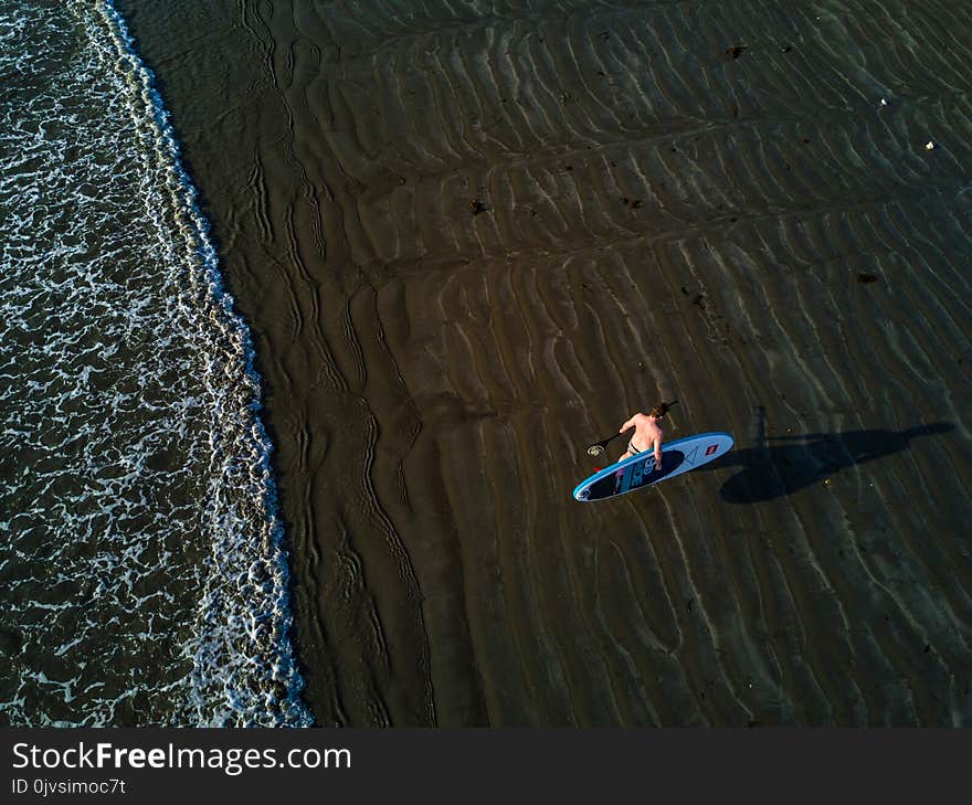 Person Holding Surfboard Near Seashore