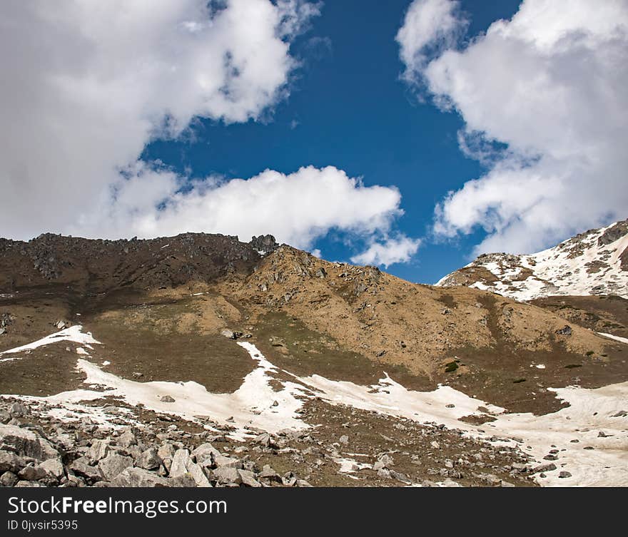 Snow Covered Hill Under Cloudy Sky at Daytime