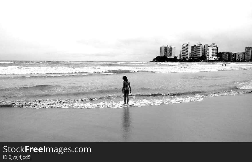 Grayscale Photo of Female Standing Seashore