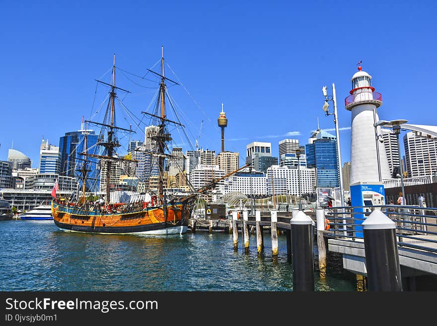 Orange Galleon Ship on Body of Water Beside City Buildings