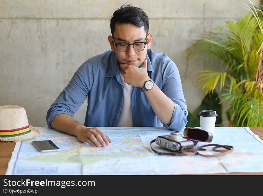 Asian Tourist Looking At Worldmap And Plans For His New Trip