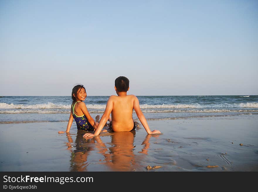 Happy children sitting on Hua Hin beach in sunny day