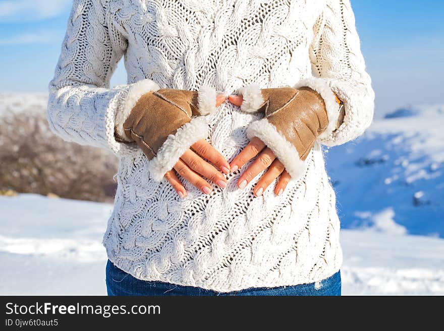 Close up woman showing heart sigmn on baby bump on a sunny winter day - maternity concept. Close up woman showing heart sigmn on baby bump on a sunny winter day - maternity concept