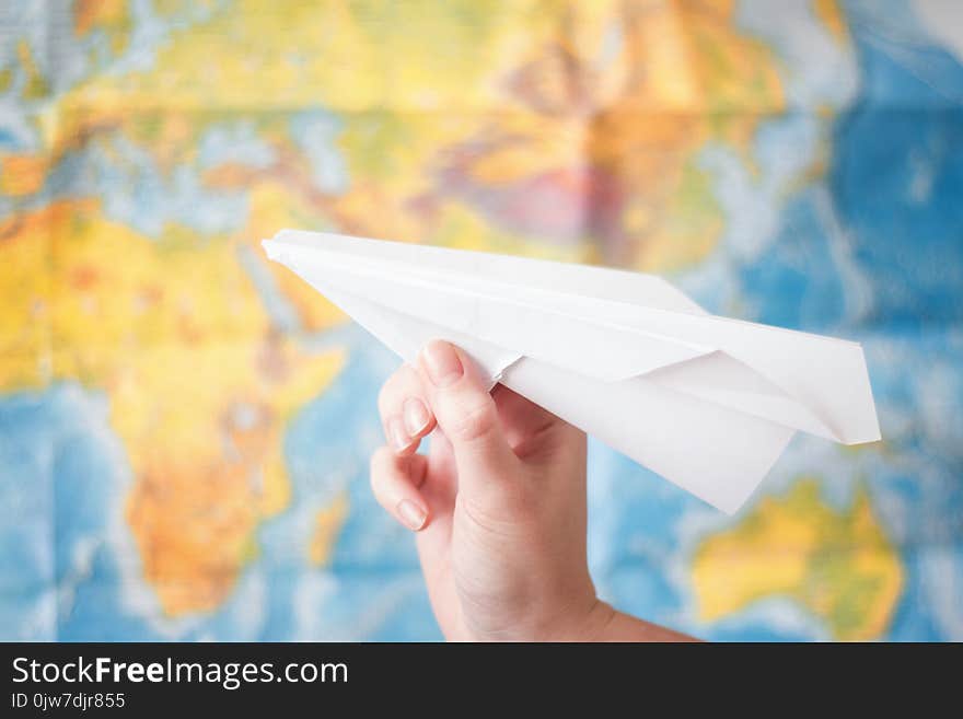 Paper airplane in hand on world map background . Travel concept