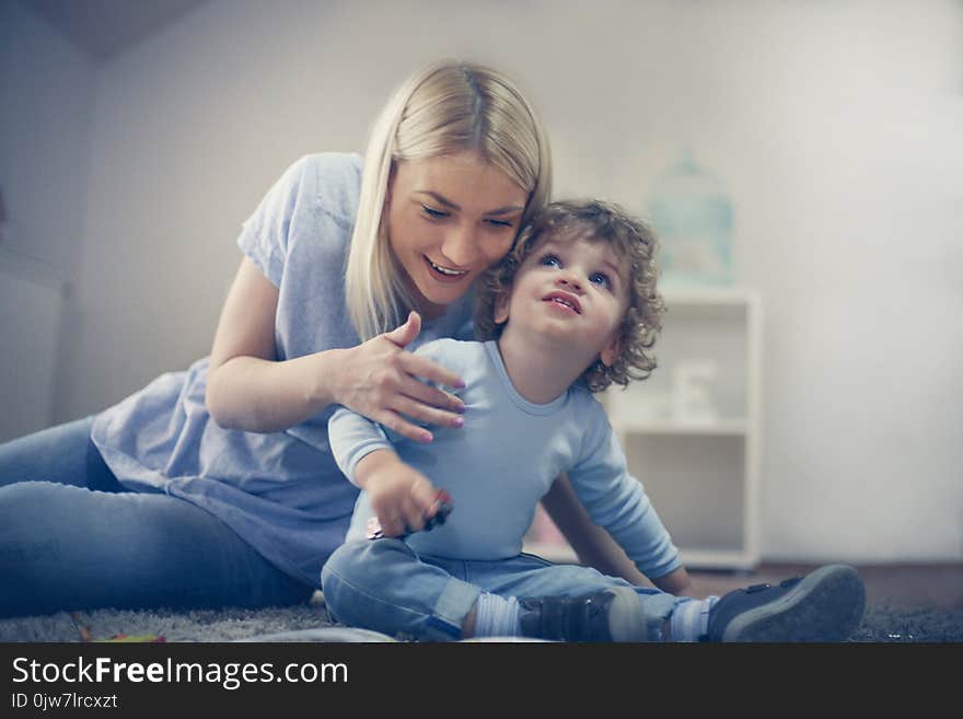 Mother playing with son. Reading him story and sitting on floor. Mother playing with son. Reading him story and sitting on floor.